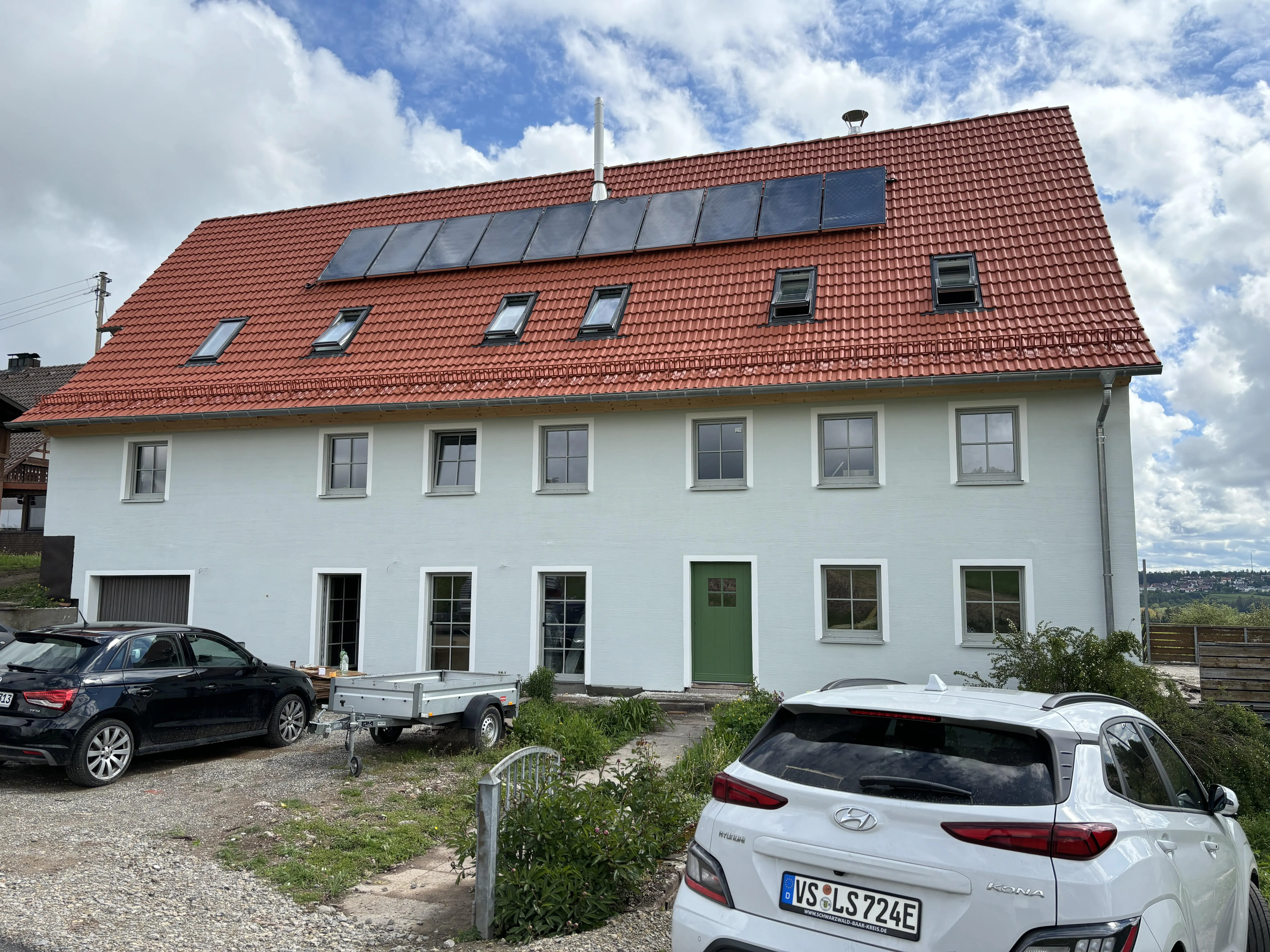 Fertig verputztes, weißes Wohnhaus mit rotem Ziegeldach und Solaranlage