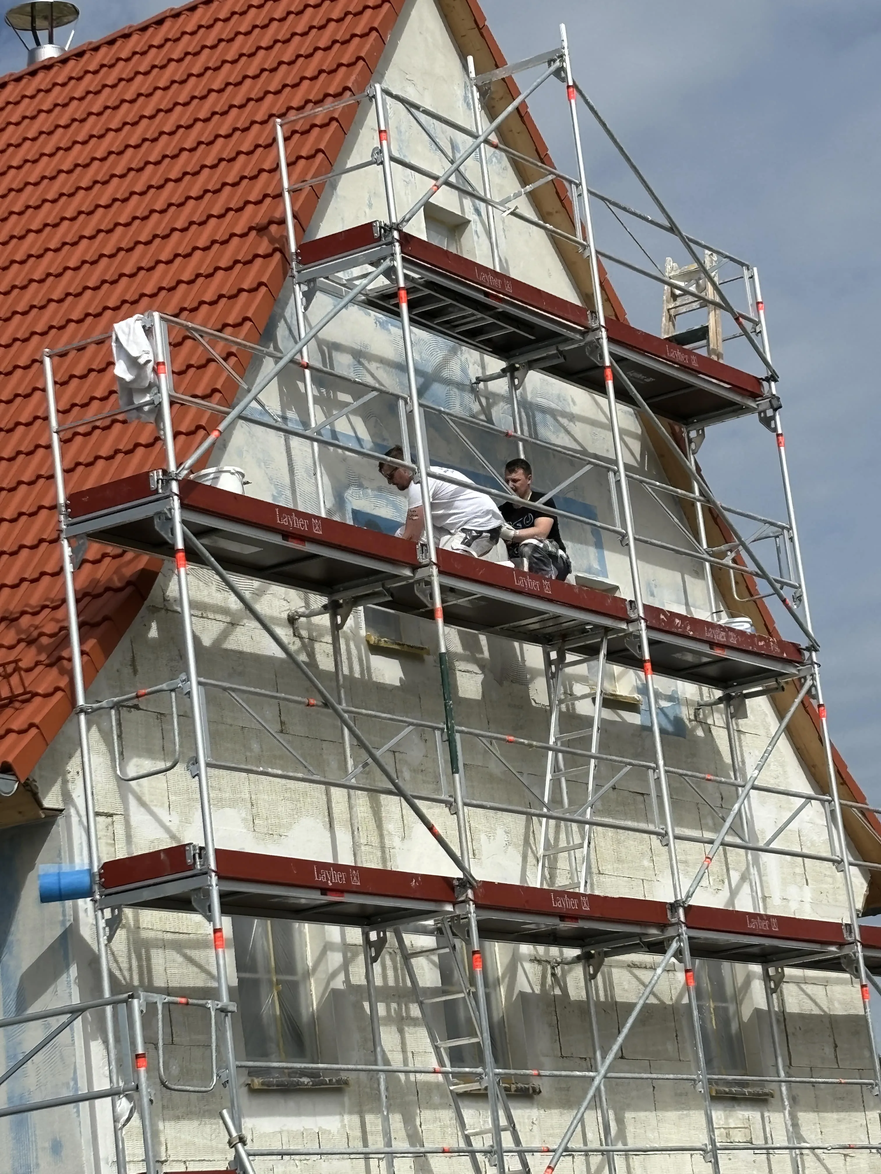 Eingerüsteter Giebel eines Hauses mit rotem Ziegeldach